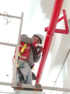 Técnico con casco instalando una abrazadera en tubería vertical