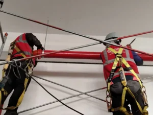 Técnicos con arnés alineando una tubería horizontal de agua contra incendio