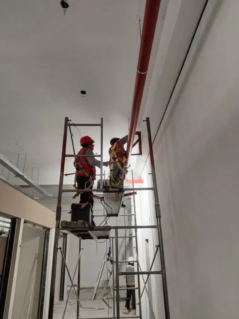 Técnicos en andamio alto trabajando en un ducto vertical