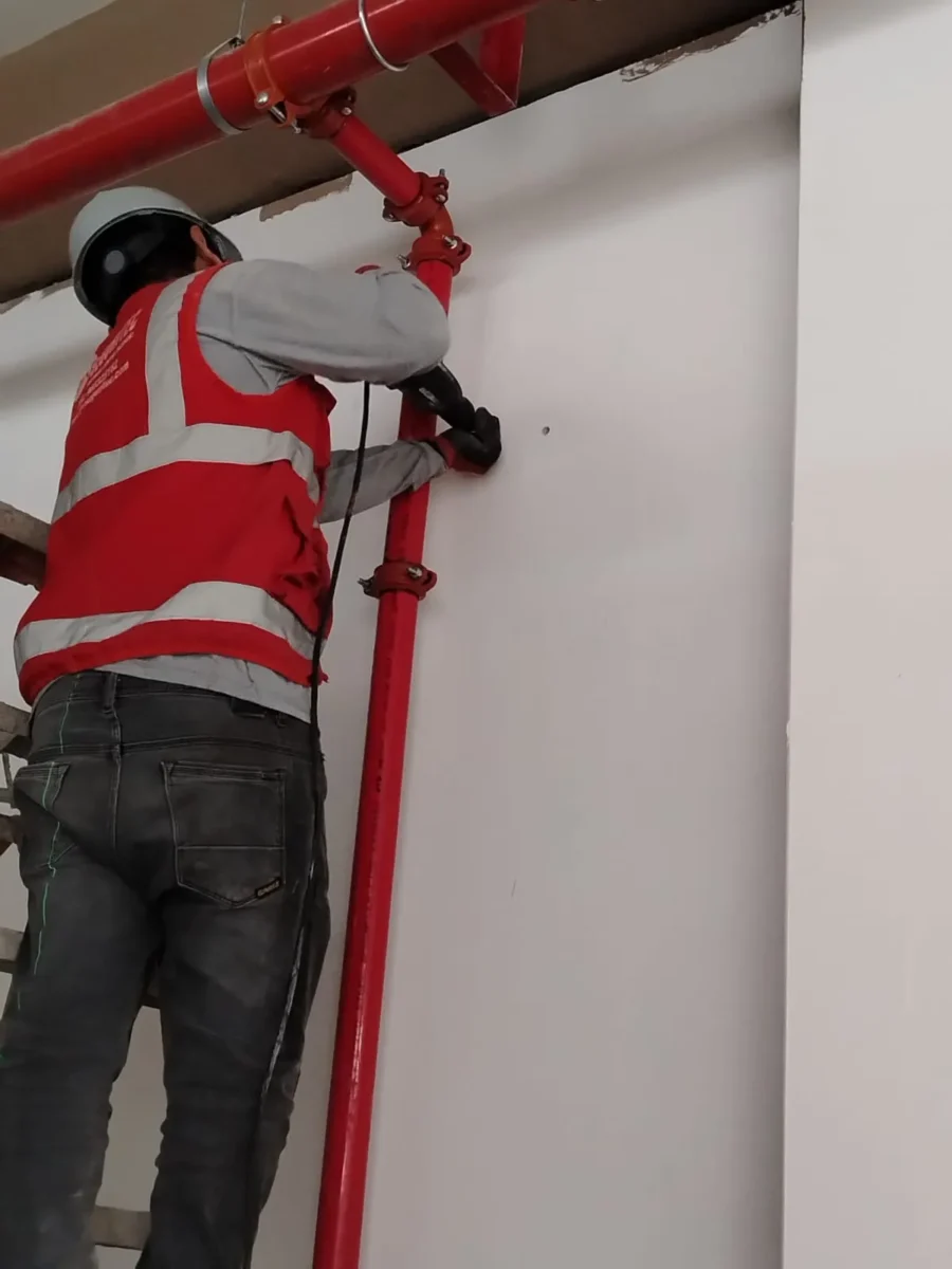 Técnico instalando una bajada vertical de tubería y su soporte en la pared