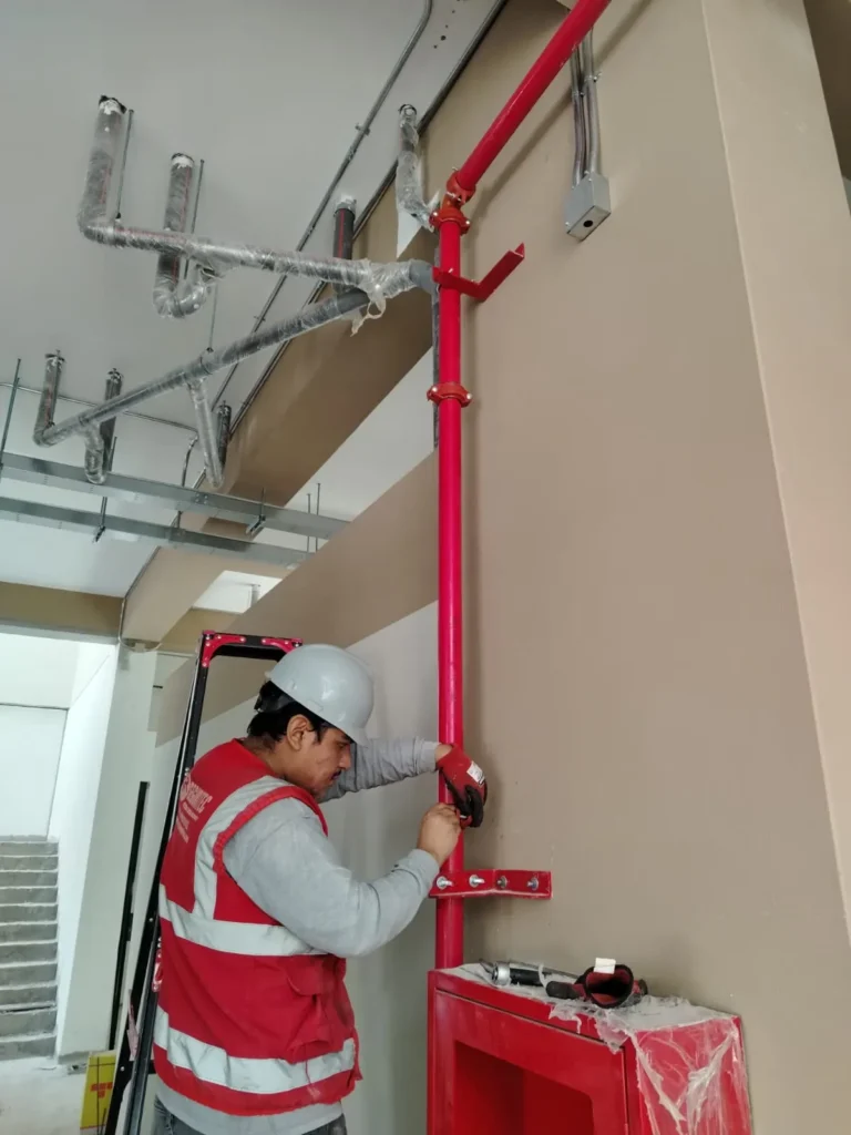 Técnico conectando la bajada de tubería a un gabinete contra incendio