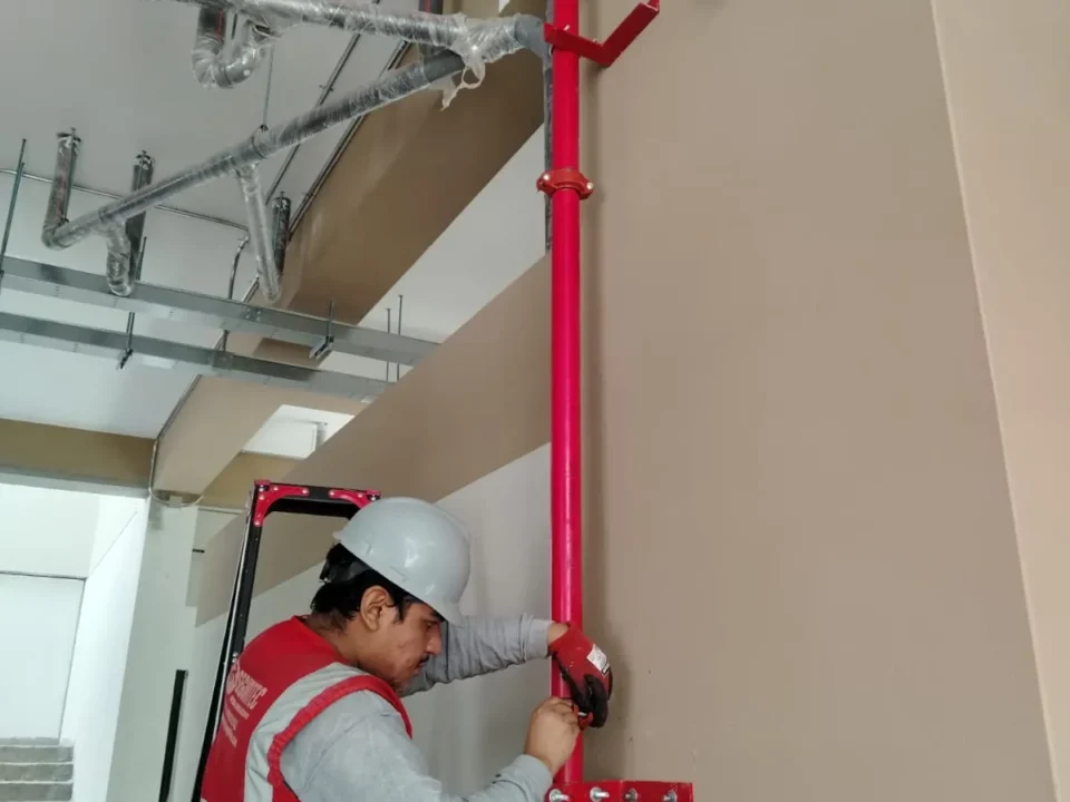 Técnico conectando la bajada de tubería a un gabinete contra incendio