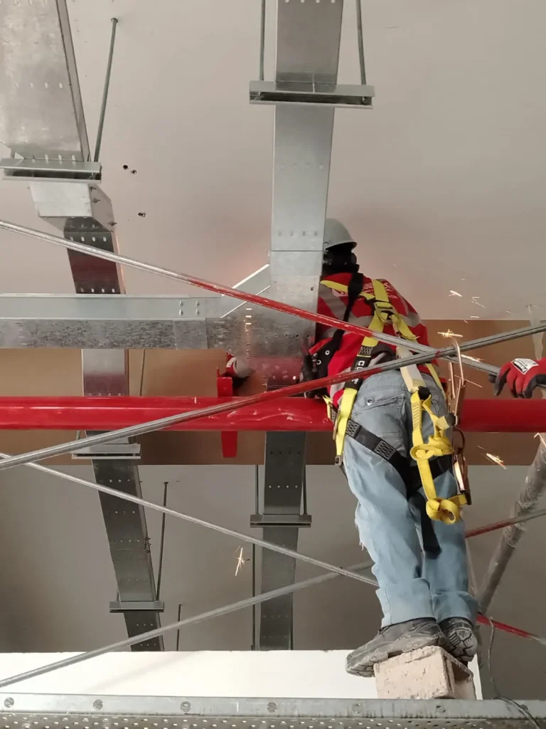 Técnico cortando tubería con amoladora sobre andamio
