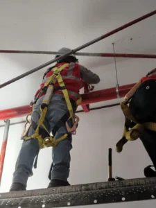 Técnicos con arnés fijando tubería horizontal en altura