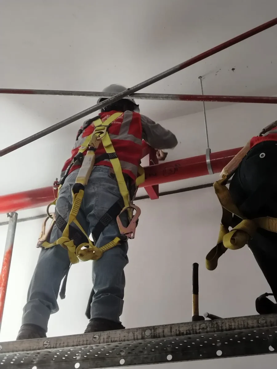 Técnicos con arnés fijando tubería horizontal en altura