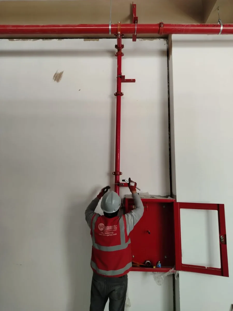 Técnico montando un gabinete contra incendio bajo la bajada de tubería