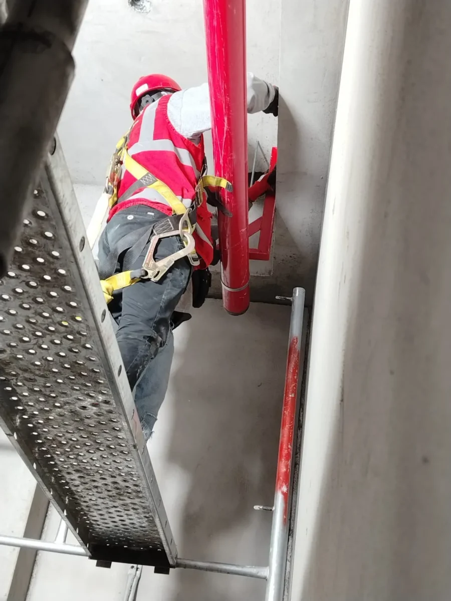 Técnico con arnés instalando un montante vertical dentro de un ducto