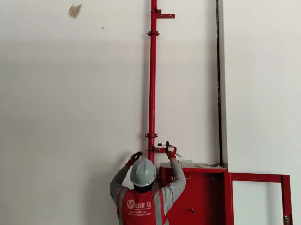 Técnico de VYR SEGURITEC conectando la tubería roja de bajada a un gabinete contra incendio en obra
